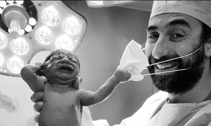 Picture of newborn baby 'trying to remove' doctor's mask is declared as 'picture of the year'